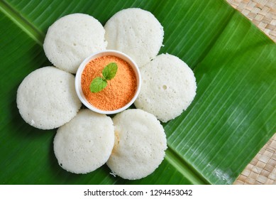 Many Idli or idly with coconut chutney powder popular breakfast of South India and Sri Lanka arranged on banana leaf. Healthy steamed cakes made by steaming fermented batter of black lentils and rice 
