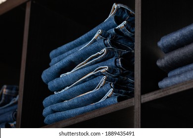 Many jeans in closet. Stack of jeans in store. 