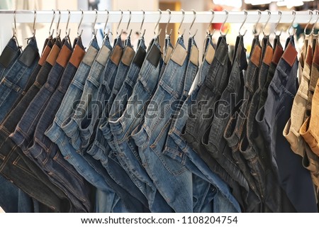 Many jeans hanging on a rack. Row of pants denim jeans hanging in closet. concept of buy , sell , shopping and jeans fashion .
