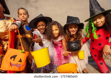 Many kids hold Halloween candy buckets and smile looking to the camera - Powered by Shutterstock