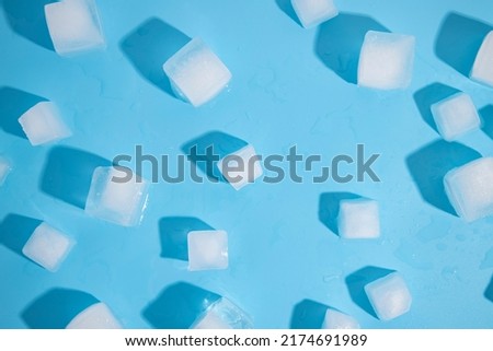 Many large ice cubes on a blue background. Top view, flat lay.