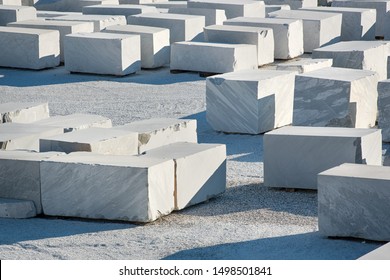 Many large rectangular blocks of white Carrara marble outdoors at a mine or quarry in Tuscany, Italy, in a concept of mining of natural resources for construction and sculpture