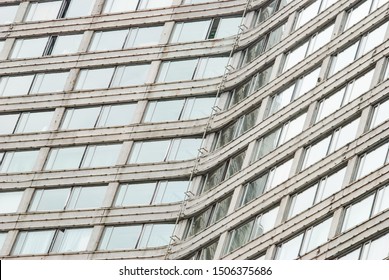Many large windows on the facade of the curved building.