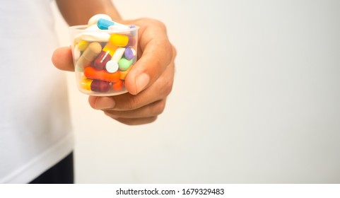 Many medicines Placed in a clear plastic canister, available in many colors and sizes, beautiful and hand-held Wearing a white shirt, black pants, gray background - Shutterstock ID 1679329483
