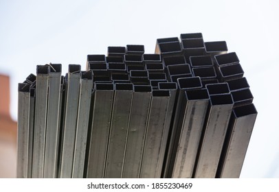 Many metal pipes stacked together on construction site during building works in city. Hollow structural section or square profile shape - Shutterstock ID 1855230469