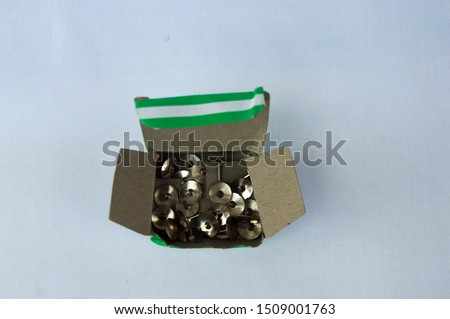 many metal thumb tack on white background in box