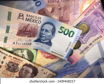 Many Mexican Pesos And Other Latin American Money Bills Spread Over A Wooden Desk Inside A Small Business Office