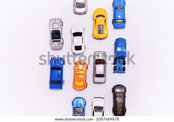 Many miniature toy cars on white background. The\
group of car toy on the road.Top view,copy space. Traffic jam\
concept with multiple toy\
cars.