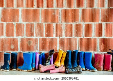 Many Muddy Colored Wellies On The Ground.