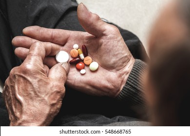 Many Multi-colored Pills In A Senior's Hands. Painful Old Age. Caring For The Health Of The Elderly