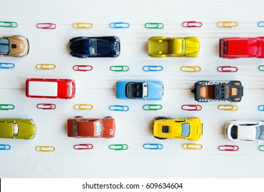 Many Multi-colored Toy Cars On White Background. The Group Of Car Toy On The Road. Small Cars On White Table, Top View With Copy Space. Traffic Jam Concept With Multiple Toy Cars On A Blackboard.