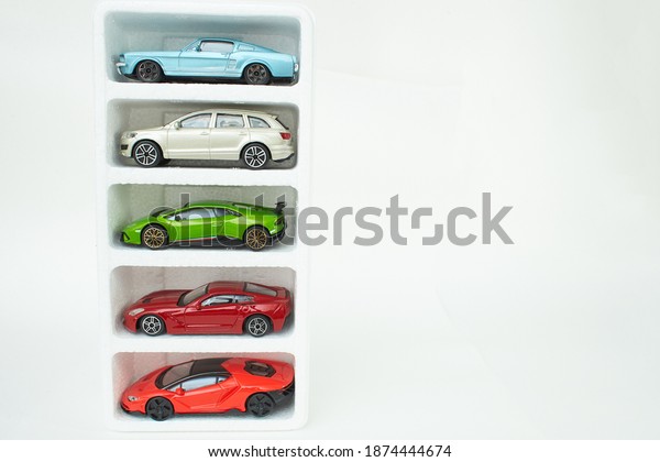 Many\
multi-colored toy cars on white background. The group of car toy.\
Small cars on white table, top view with copy\
space.