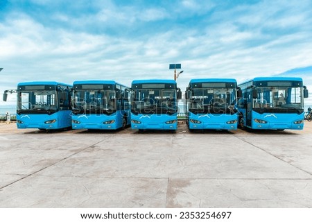 Many new energy electric buses are neatly parked in the outdoor parking lot