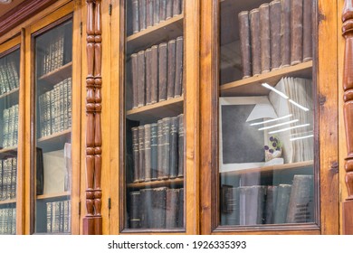 Many old books on the shelves of the university library. Retro books are behind the glass of a bookcase.