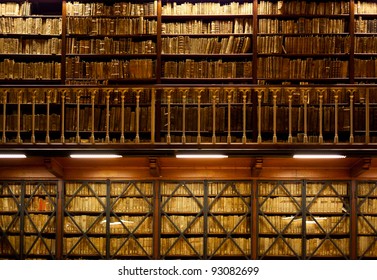 Many Old Books Are Standing On Wooden Shelves In Two-tier Library , With Handrail On Foreground