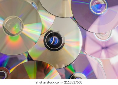 Many old CDs represent technology from the 90s. Stacks of CDs, old songs and old movies. which had been used before and placed on a white table. closeup, selective focus