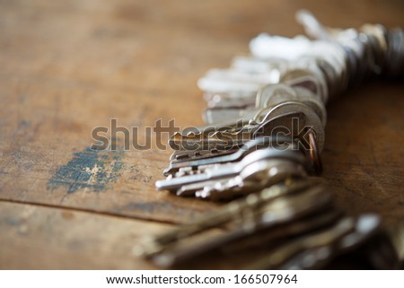 Many old keys on a well used old wooden desk. Security and encryption, concept image.