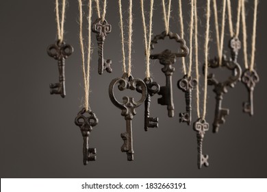 Many old-fashioned keys hanging on dark grey background