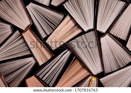 Many open old multicolored books stand on the bookshelf