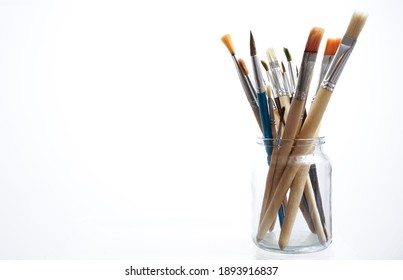 Many Paint Brushes In A Glasses Jar Isolated On White  Background.