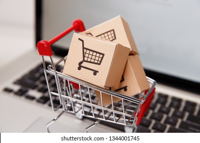 Many paper boxes in a small shopping cart on a laptop keyboard. Concepts about online shopping that consumers can buy things directly from their home or office just using a few clicks via web browser.