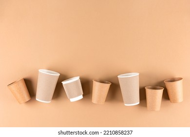 Many Paper Coffee Cups Over Light Brown Background With Copy Space. Eco Paper Cups For Hot Beverages To Go. Sustainable Take Away Food Packaging Concept. View Above