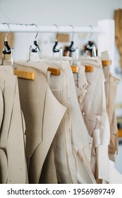 Many paper sewing patterns for different clothes hanging on the rack in sewing factory background. Clothing pattern, manufacture on sewing factory. Tailoring, small business