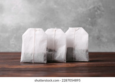 Many paper tea bags on wooden table, closeup