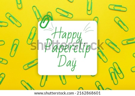 Many paperclips on yellow background. Greeting card for National Paperclip Day
