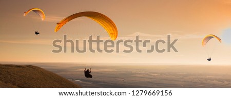 Many of paragliders flying in the evening sunrise.