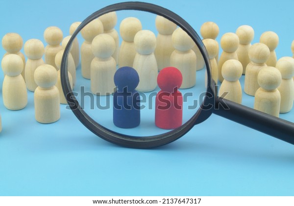 Many people figures and two red and blue leaders\
under magnifying glass.