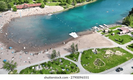 Many people utilizing the beach at this state park as numerous individuals are scattered across the sand and in the water swimming.