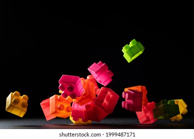 Many Plastic Building Blocks Falling Into A Dark Surface And With A Black Background