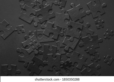 Many puzzles are randomly scattered on the plane. Photo of black puzzles on a black background, business background