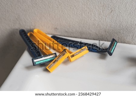 Many razors are old with rusty blades that have been used before placed on the edge of the basin in the bathroom.