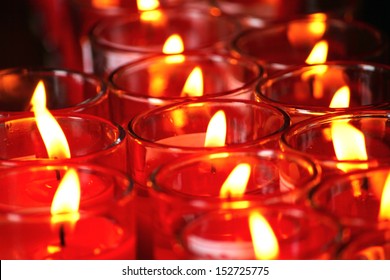 Many red votive candles light the darkness in church
