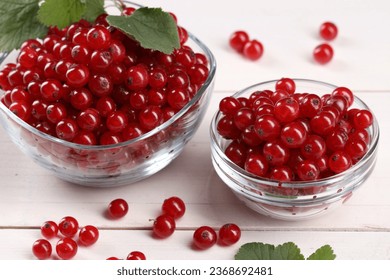 Many ripe red currants and leaves on white wooden table - Shutterstock ID 2368692481