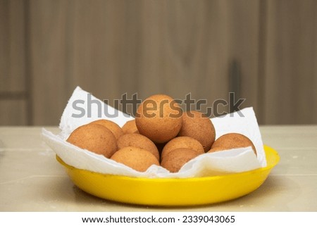 Many round Colombian fritters on a plate on a home table, freshly prepared, golden and fluffy, traditional snack from Antioquia and from different Colombian places.