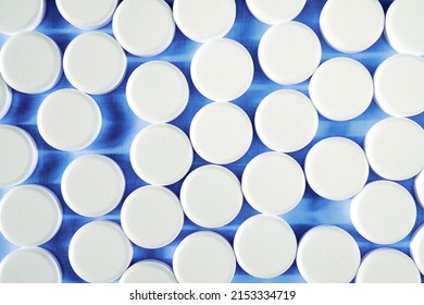 Many round white small tablets photographed close-up.