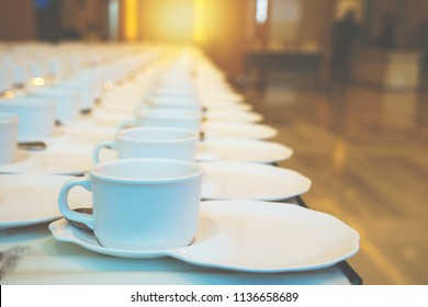 Many Rows Clean White Coffee Cup, Tea Spoon And Saucer. Empty Mug Set In Row Prepare For Coffee Break Service Of Seminar Or Party Event At Hotel Or Conference Office Building Room.