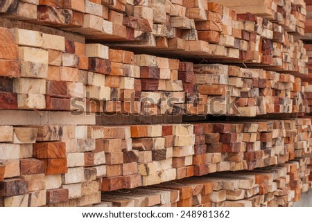 Many rows of timber are stacked high at a sawmill.