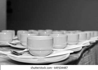 Many rows of white ceramic coffee or tea cups, black and white tone.