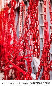 Many rusty red chains with hooks are fastened and hold containers with cargo on the ship.