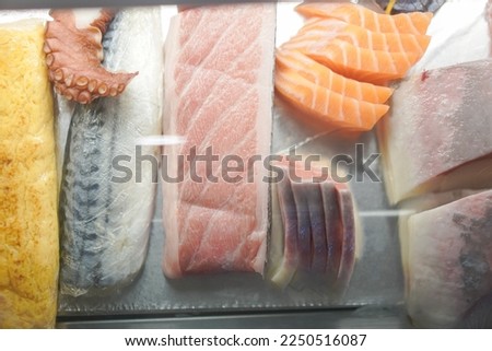 Many of Sashimi fresh food as squid and fish in Showcase at the bar counter of Sushi restaurant. Close up.
