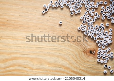 Many scrabble letters from the entire alphabet on a raw light colored wood backdrop for your design, photo, title or Illustration.