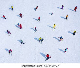 Many skiers and snowboarders are located on the side of the mountain - Shutterstock ID 1574455927