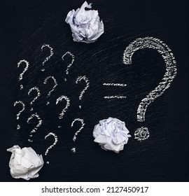 Many small question marks and one large question mark are drawn in white chalk on a rough black background. Concept of thinking or problem solving. Many unresolved issues or deadlock