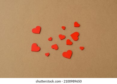 Many small wooden red hearts on a kraft paper background. Love background, Valentine`s day concept 