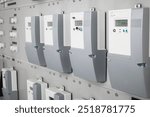 Many smart meters in electrical room of building with defocused ceramic fuses. Digital meter transmits energy consumption. Electric energy use is recorded and transmitted automatic. Selective focus.