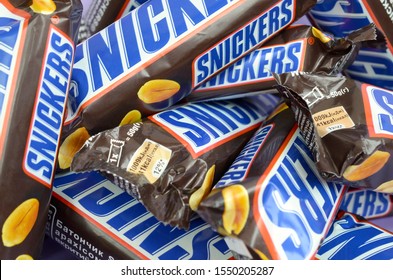 Many Snickers Chocolate Bars Stacked Close Up. Snickers Bars Are Produced By Mars Incorporated. Snickers Was Created By Franklin Clarence Mars In 1930